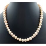 A 16" peach lustre freshwater pearl necklace with pink glass beads and silver tone T bar toggle