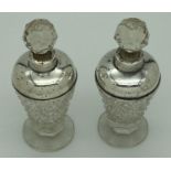 A pair of early 20th century cut glass scent bottles with silver collars and shoulders. Worn