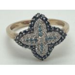A 9ct gold flower design diamond cluster ring set with clear, black and blue diamonds. One small