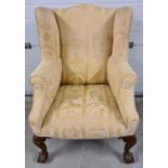 A vintage wooden framed wing back arm chair with ball & claw carved front feet. Reupholstered in a