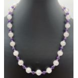 An 18" rose quartz and amethyst beaded necklace with silver tone bayonet clasp. Rose quartz beads