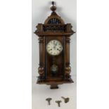 An antique wooden cased wall clock with turned finial & column detail and RA pendulum. Glass