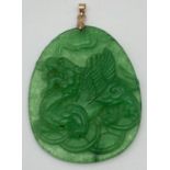 A carved jade pendant, with yellow metal bale, designed with Chinese dragon carving to one side.