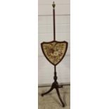An antique Regency mahogany pole screen with embroidered felt floral panel in a shield shaped frame.