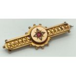 A Victorian 9ct gold brooch set with central pink stone, seed pearls and filigree detail. Hallmarked