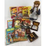 A box of assorted misc toys and books, to include vintage annuals, ceramic doll, playing cards and