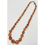 An graduating amber flat oval bead necklace with silver spring clasp. Approx. 20 inches long. Silver