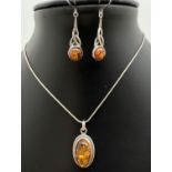 An oval shaped amber pendant on an 18" silver snake chain with lobster style clasp. Together with