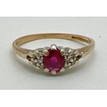 A vintage 9ct gold ruby and diamond dress ring. Central oval cut ruby with 5 small diamonds to