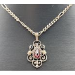 A pierced work drop style pendant set with a teardrop cut garnet, on a 34" Figaro silver chain.