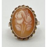 An unmarked yellow metal dress ring with carved floral design cameo in a twist style setting.