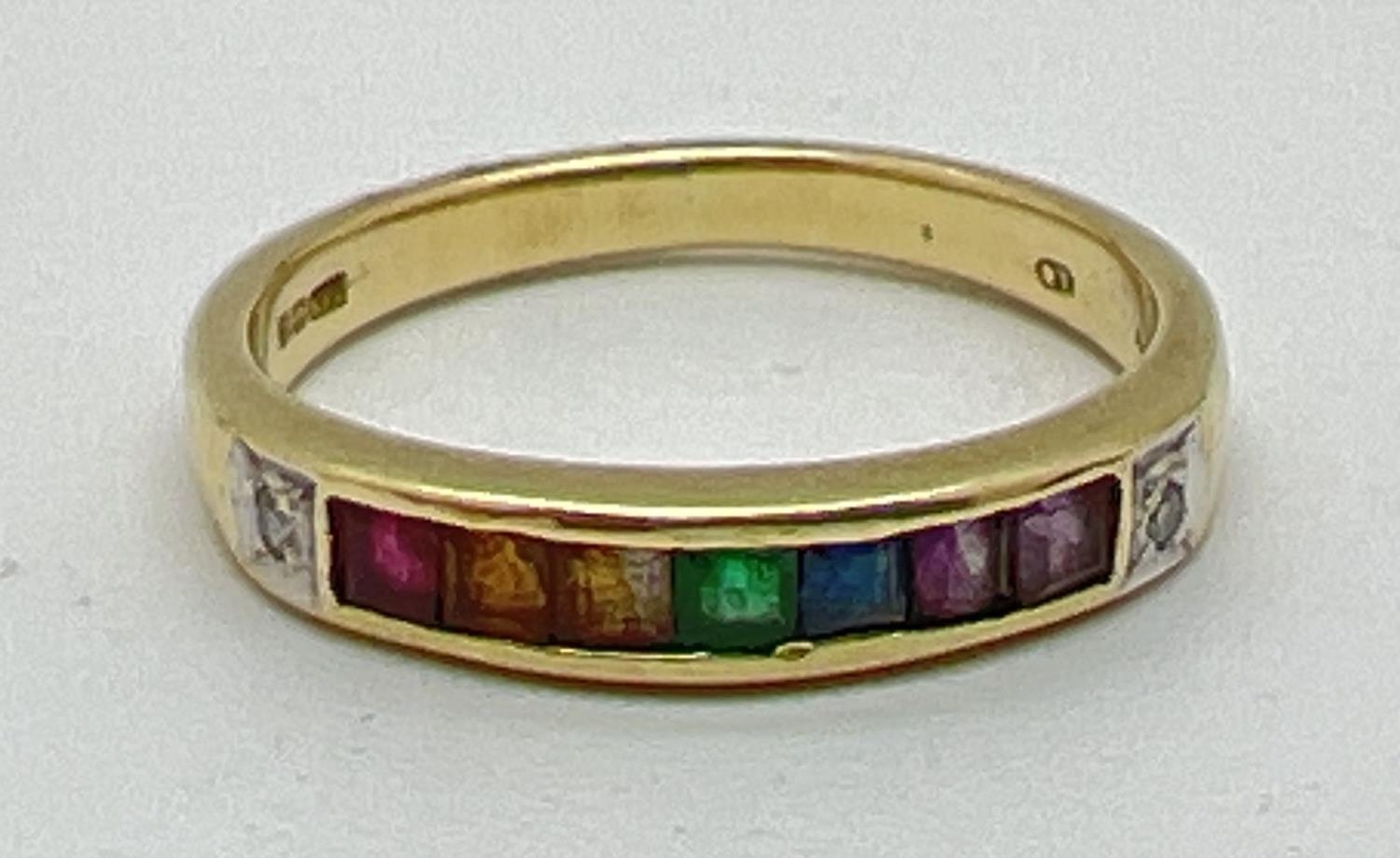 A 14ct gold ring set with 7 square cut channel set rainbow gemstones and flanked by diamonds.