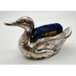 A large Edwardian silver novelty pin cushion in the form of a duck, with worn blue fabric cushion.