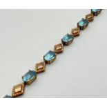 A 9ct gold oval cut blue topaz and diamond shaped alternating link bracelet with lobster style