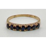 A 9ct yellow gold half eternity ring set with 7 round cut sapphires. Fully hallmarked inside band,