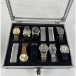 A metal and perspex watch display case containing 8 varying style wristwatches. To include Aurora,