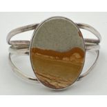 A vintage silver cuff style bangle set with a large oval cut agate stone. Back marked Sterling.