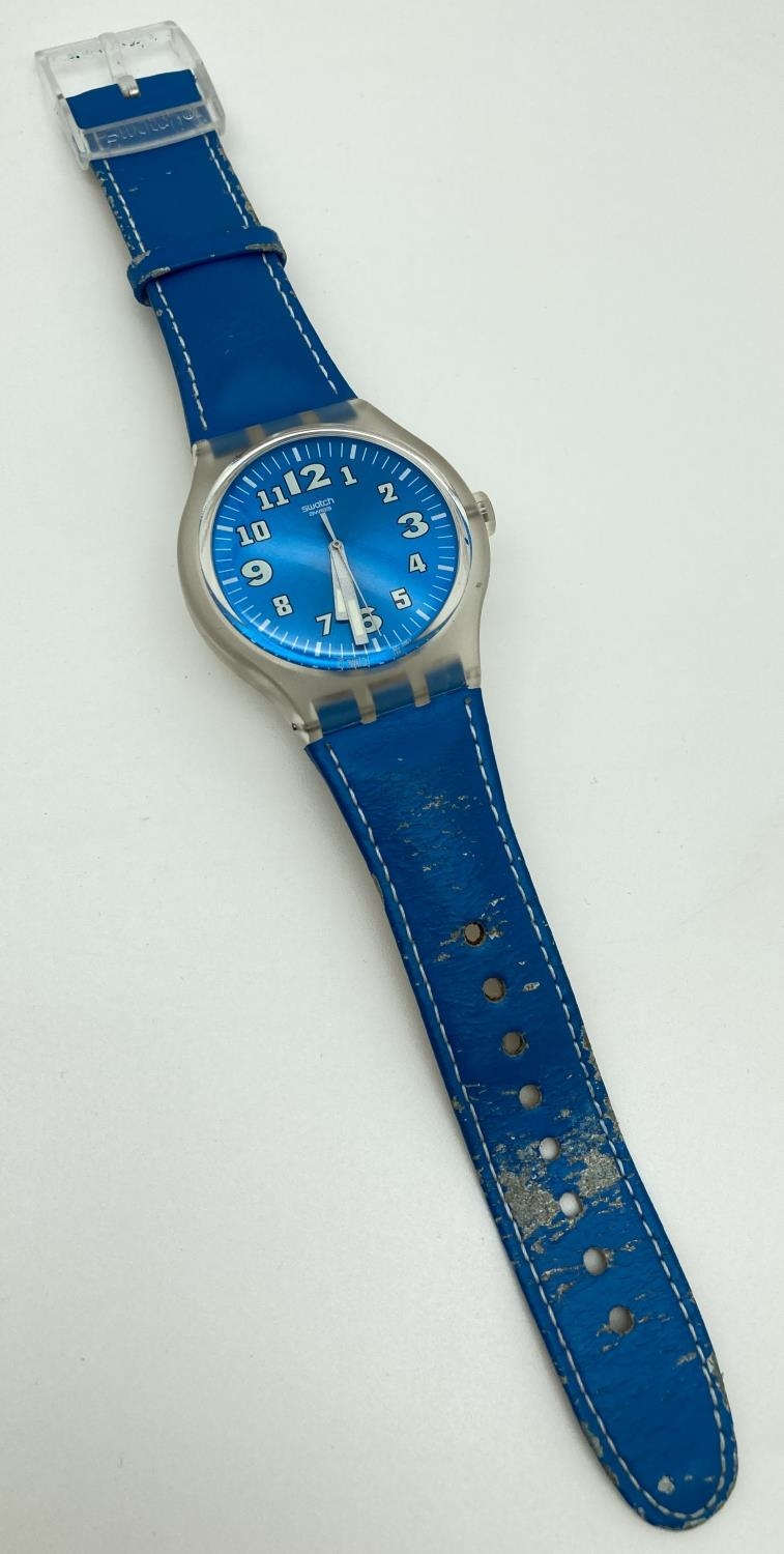 A unisex S216 Swatch watch with metallic blue face and original blue leather strap. Luminescent
