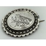 An early 20th century oval shaped white metal brooch with engraved song bird detail. Hooked C