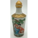 A small Chinese ceramic snuff bottle with painted erotic scene. Gilt painted stopper and top rim.