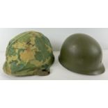 A US Vietnam era M1 steel helmet with bullet damage, complete with camo cover, Firestone liner and