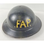 A WWII British Home Front MkII steel helmet painted black and labelled in yellow 'FAP' to front