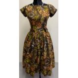 A vintage 1950's cotton day dress in an abstract brown and green floral pattern with cinched in