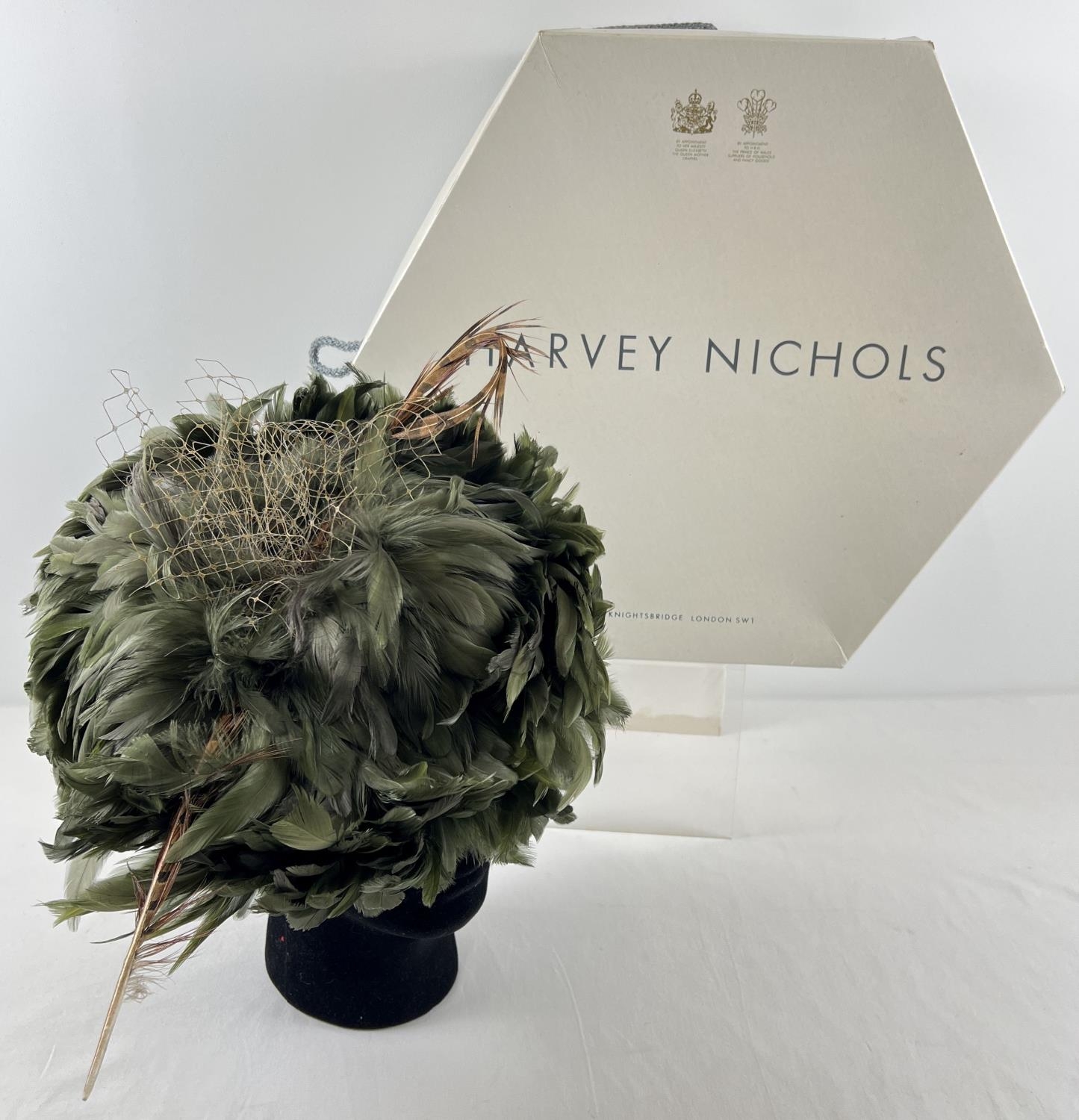 A green feather fascinator style hat with pheasant feather and net detail. Together with a Harvey