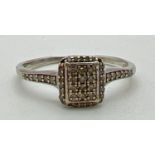 A 9ct white gold and diamond set dress ring. Square shaped mount set with 35 small round cut