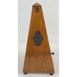 A vintage wooden cased Maelzel metronome raised on tripod wooden feet and with brass plaque to door.