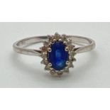 A 18ct white gold, sapphire and diamond dress ring. Central oval cut sapphire surrounded by small