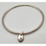 A modern silver thin bangle with oval dangle charm engraved with initial N. Hallmarked Birmingham