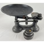 A set of cast metal weighing scales with pan and a collection of weights.