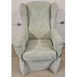 A vintage wooden framed wing back armchair, reupholstered with green foliate design material.