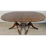 A large reproduction dark wood, oval shaped, extending dining table with brass inlaid detail. Turned
