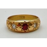 An 18ct gold gypsy style ring set with a central garnet and 2 diamonds. Stones set with claws and in