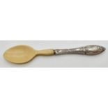 A vintage white metal handled baby spoon with floral decoration throughout handle and original