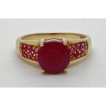 A modern design 9ct gold ruby set dress ring. Central round cut ruby with 8 small round cut rubies