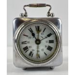 An antique wind up bedside alarm clock with enamelled face and bevel edged glass. A small silver