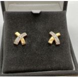 A pair of 18ct gold and diamond "Kisses" earrings. Cross style stud earrings each set with 3 small
