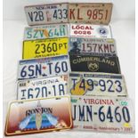 A collection of 12 assorted painted aluminium plates, mostly US automobile plates.