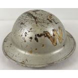 A WWII British Home Front steel helmet with early oval pad, painted silver over khaki. Labelled W