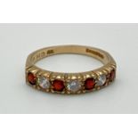 A vintage 9ct gold half eternity style ring set with alternating round cut garnets and cubic