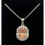 A 925 silver oval shaped pendant set with a central pale orange cubic zirconia surrounded by 12