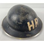 A British Home Front MkII WWII steel helmet painted black and labelled in white HR for Heavy Rescue.