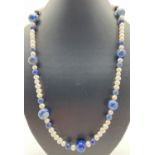 A 25" freshwater pearl and lapis lazuli beaded necklace with silver tone S shaped clasp. Retired