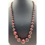 A 21" beaded necklace made from graduating red Tigers Eye beads. With silver tone S shaped hook