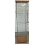 A modern square shaped glass cabinet with front opening full sized door and 3 interior glass