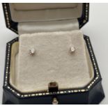 A pair of boxed 18ct gold & diamond stud earrings. Each earring holds a round cut 0.05ct diamond.