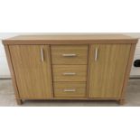 A modern light wood effect, sideboard with 2 cupboards and 3 central drawers. Long silver coloured